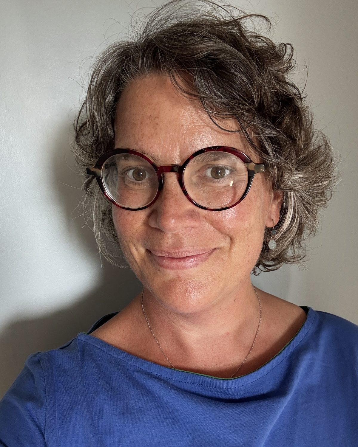 Portrait de Sixtine Pigeard Evrain, cheveux courts et lunettes rondes, souriante.